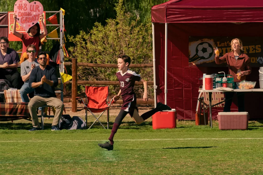 2022 Disability News young boy playing soccer while people cheering behind him