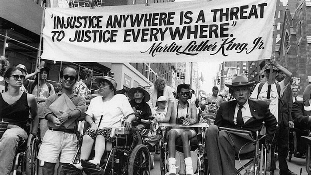A group of people in wheelchairs holding a banner during the Disability Rights Movement. 
